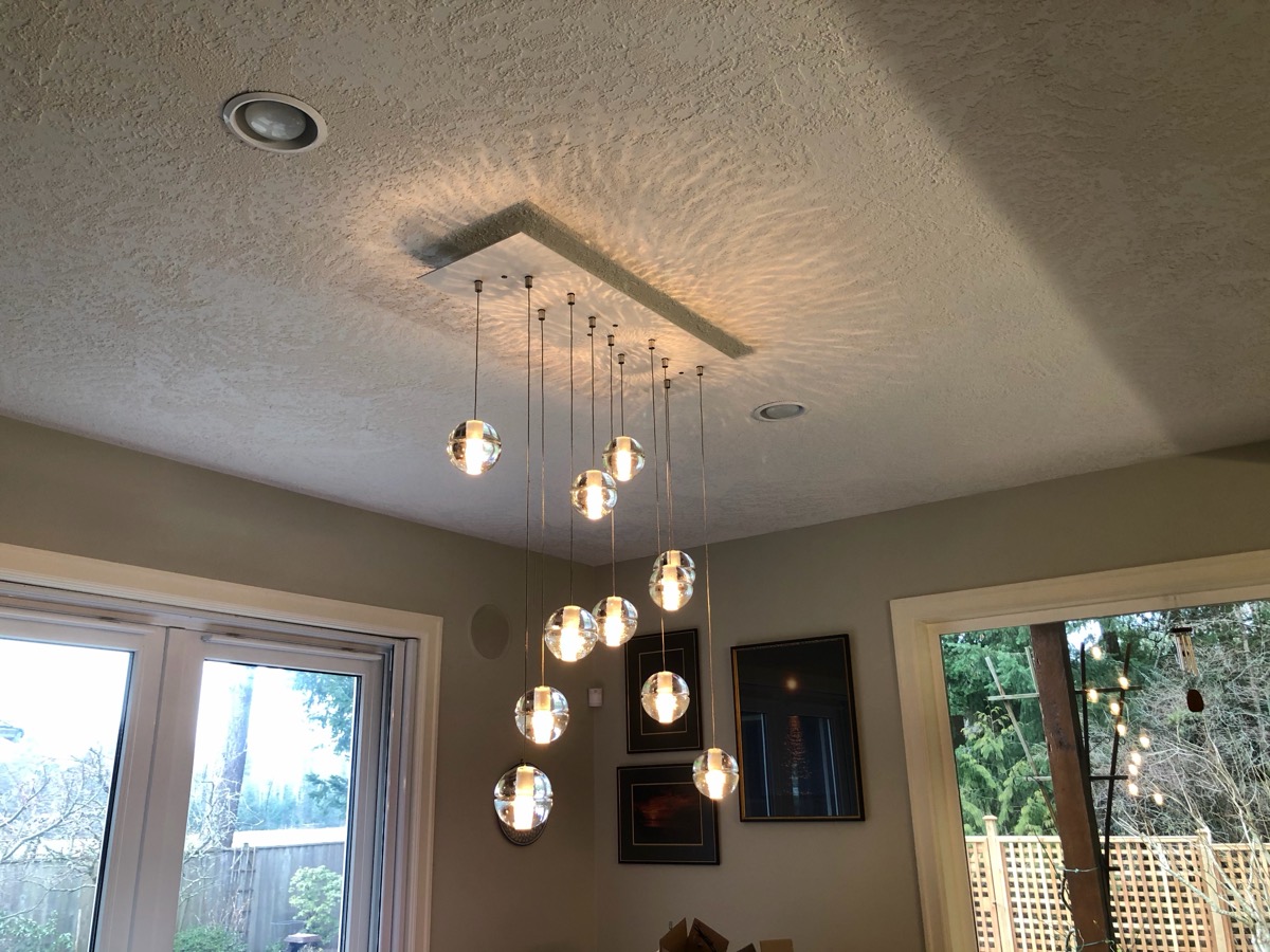 A cluster of glass bubble pendants and pot lights over a dining area.