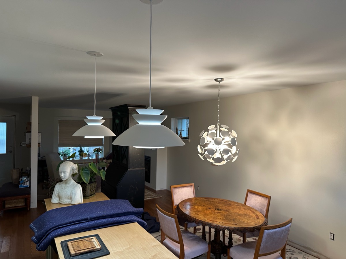 Tiered dome pendants and a sculptural chandelier over a dining area.