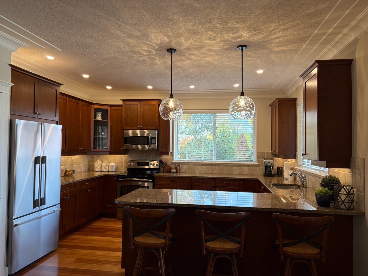 Glass globe pendants and pot lights over a kitchen peninsula and eating bar.